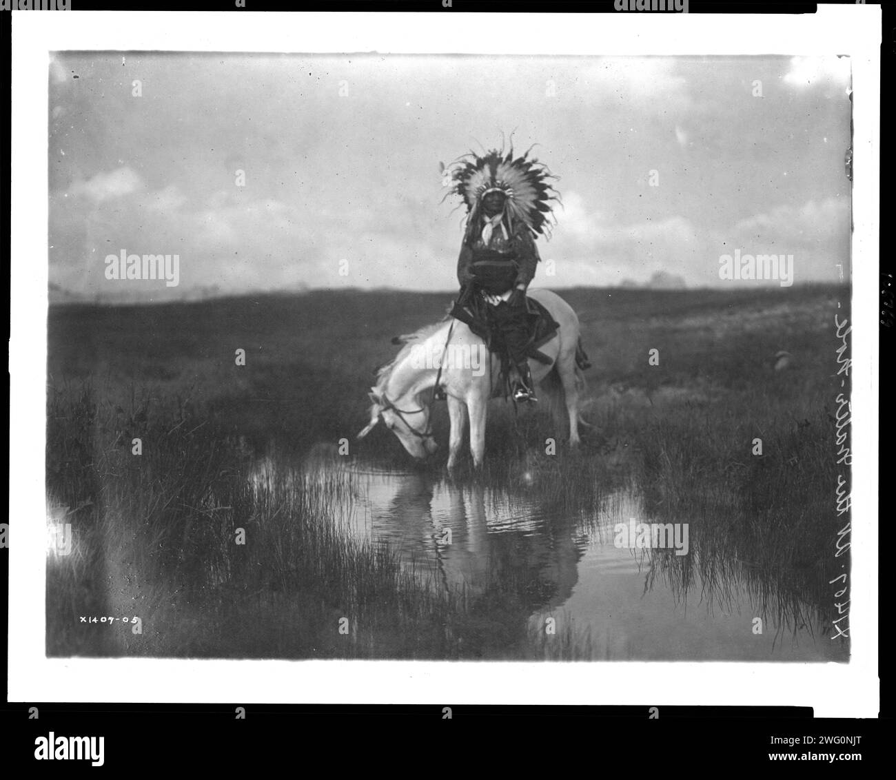 Das Tal der Rosebud, 1905. Das Foto zeigt einen Cheyenne-Indianer, der einen Kopfschmuck trägt, zu Pferd an einem Wasserbecken. Stockfoto