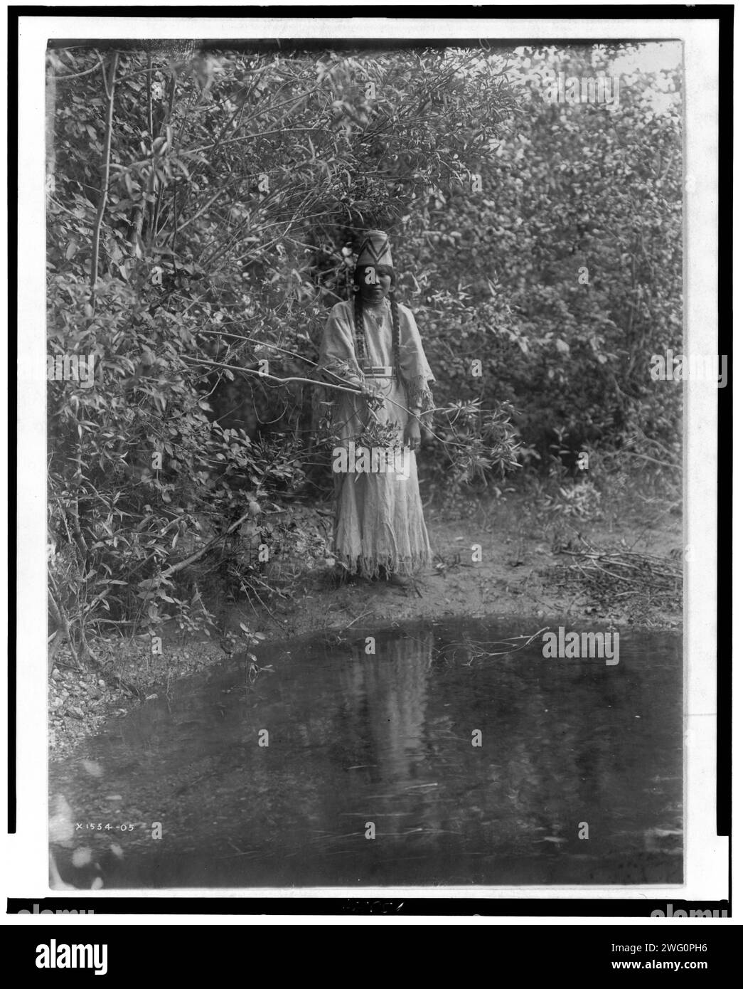 Aus den Tiefen des Waldes trat eine indische Jungfrau, 1905. Nespelim-Frau, die am Ufer steht. Stockfoto