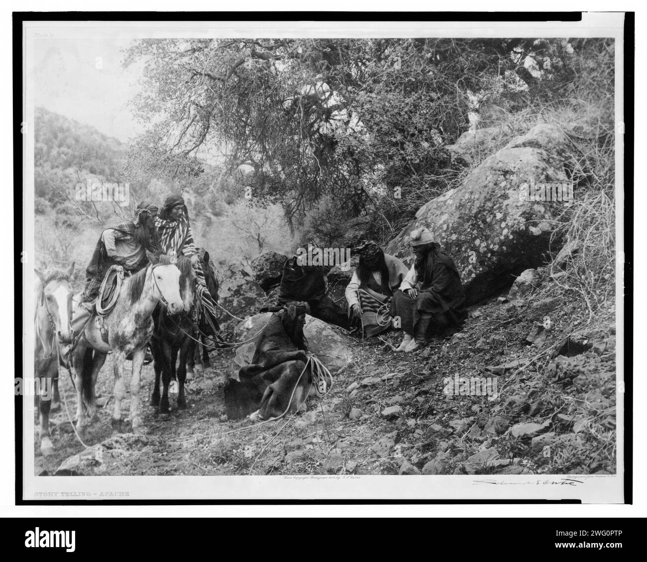 Geschichtenerzählen, 1906. Eine Gruppe von Apachen-Männern, zwei zu Pferd, andere sitzen, zuhören und zuschauen, während ein Mitglied der Partei den Boden mit einem Stock markiert. Stockfoto