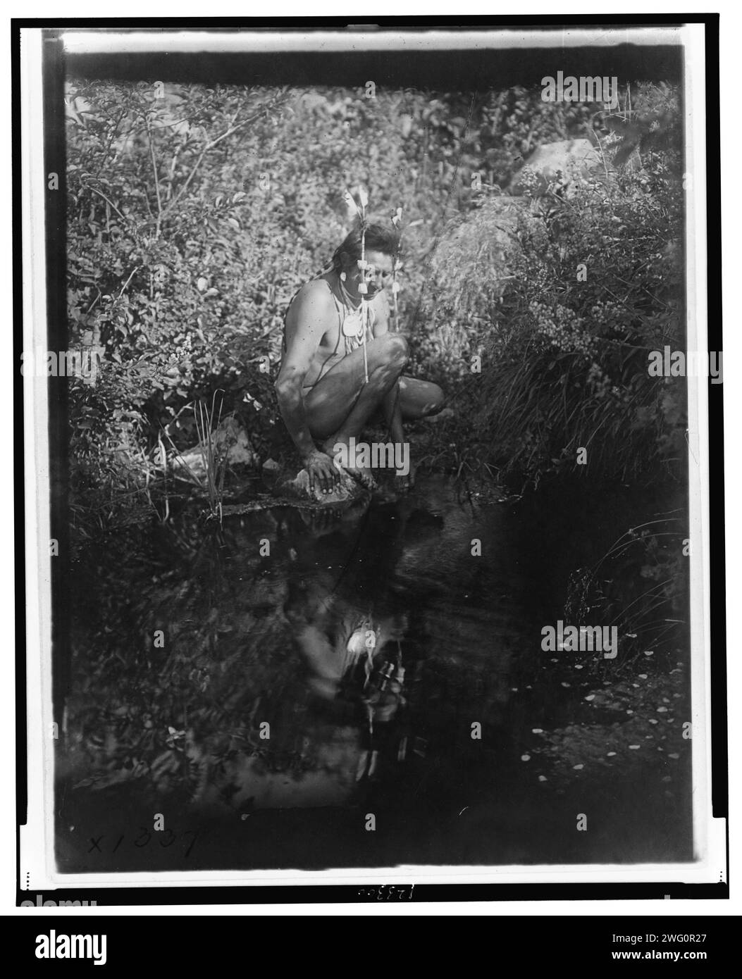 Der Drink, um 1905. Krähen-Indianer kniend neben Wasser und blickend auf sein Spiegelbild. Stockfoto