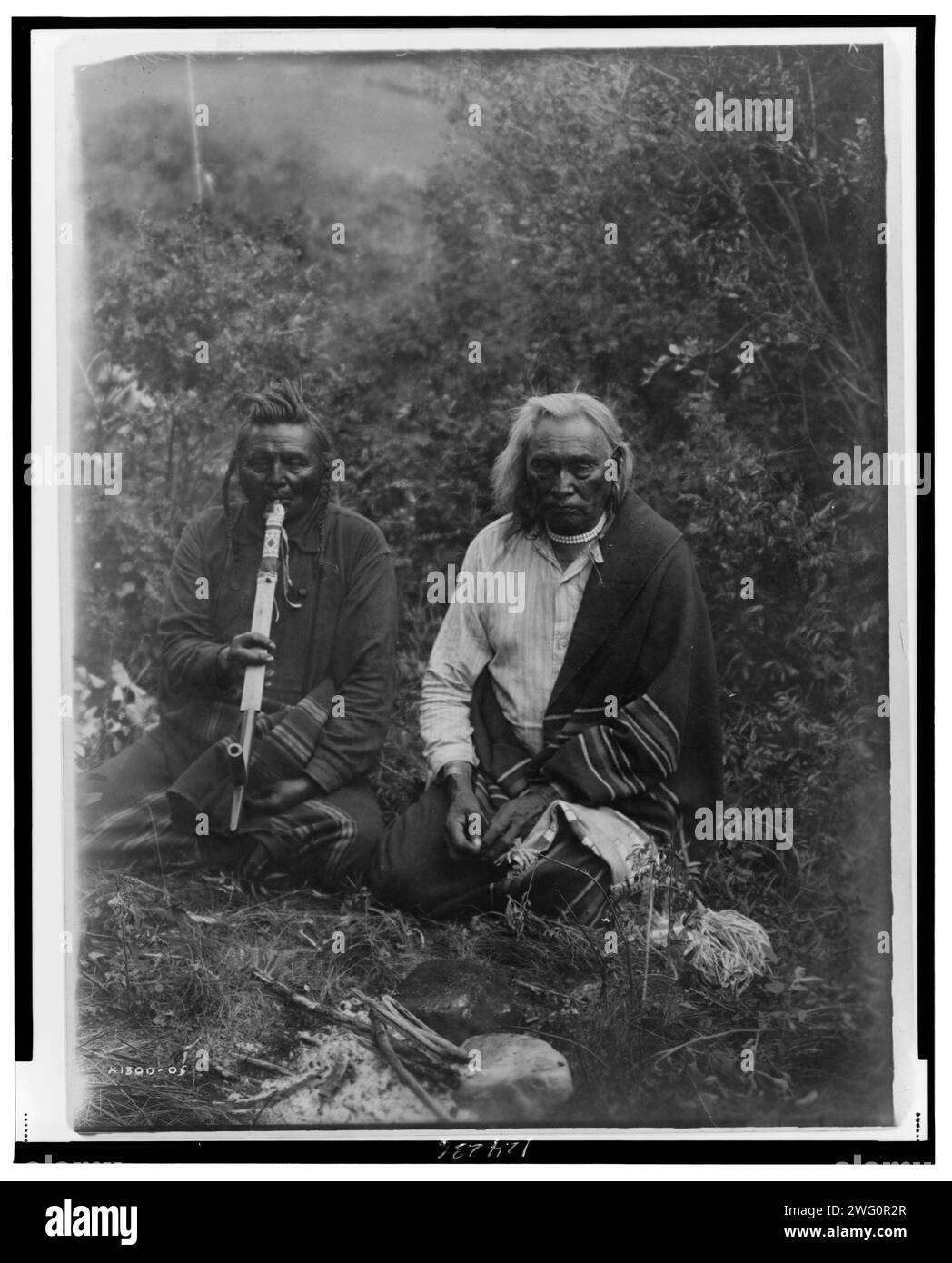 Ein Rauch, c1905. Zwei Krähenindianer in Montana, die auf dem Boden sitzen, einer raucht eine Pfeife. Stockfoto