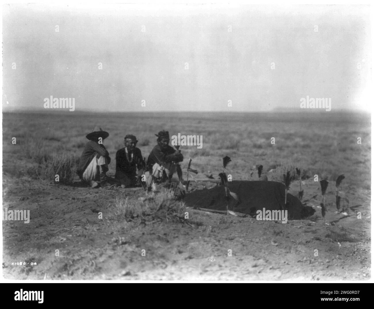 Yeibichai Sweat-Navaho, 1905. Drei Navajo-Männer sitzen und beobachten einen Mann, der mit einer Decke bedeckt ist (?) Mit Stangen mit Federn befestigt. Stockfoto