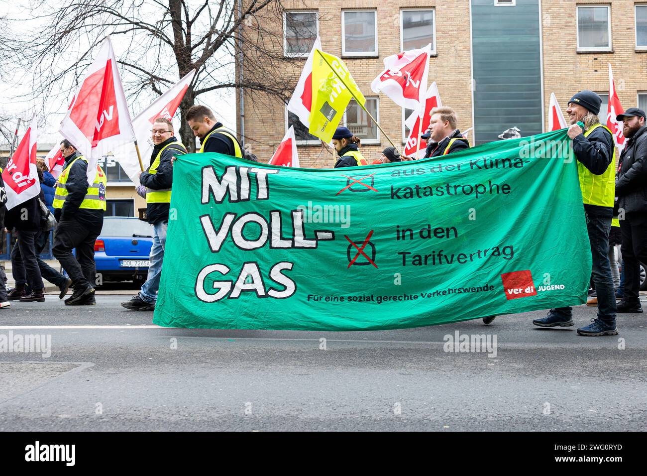 Hannover, Deutschland. Februar 2024. Die Teilnehmer einer Verdi-Demonstration laufen durch die Innenstadt von Hannover mit einem Banner mit der Aufschrift „volle Geschwindigkeit voraus aus der Klimakatastrophe - in den Tarifvertrag - für eine sozial gerechte Trendwende im Verkehr“. Die gewerkschaft Verdi hatte die Beschäftigten des öffentlichen Verkehrs in mehr als 80 Städten dazu aufgerufen, im bundesweiten Lohnstreit in regionalen Verhandlungen einen Warnstreik zu führen. Quelle: Michael Matthey/dpa/Alamy Live News Stockfoto