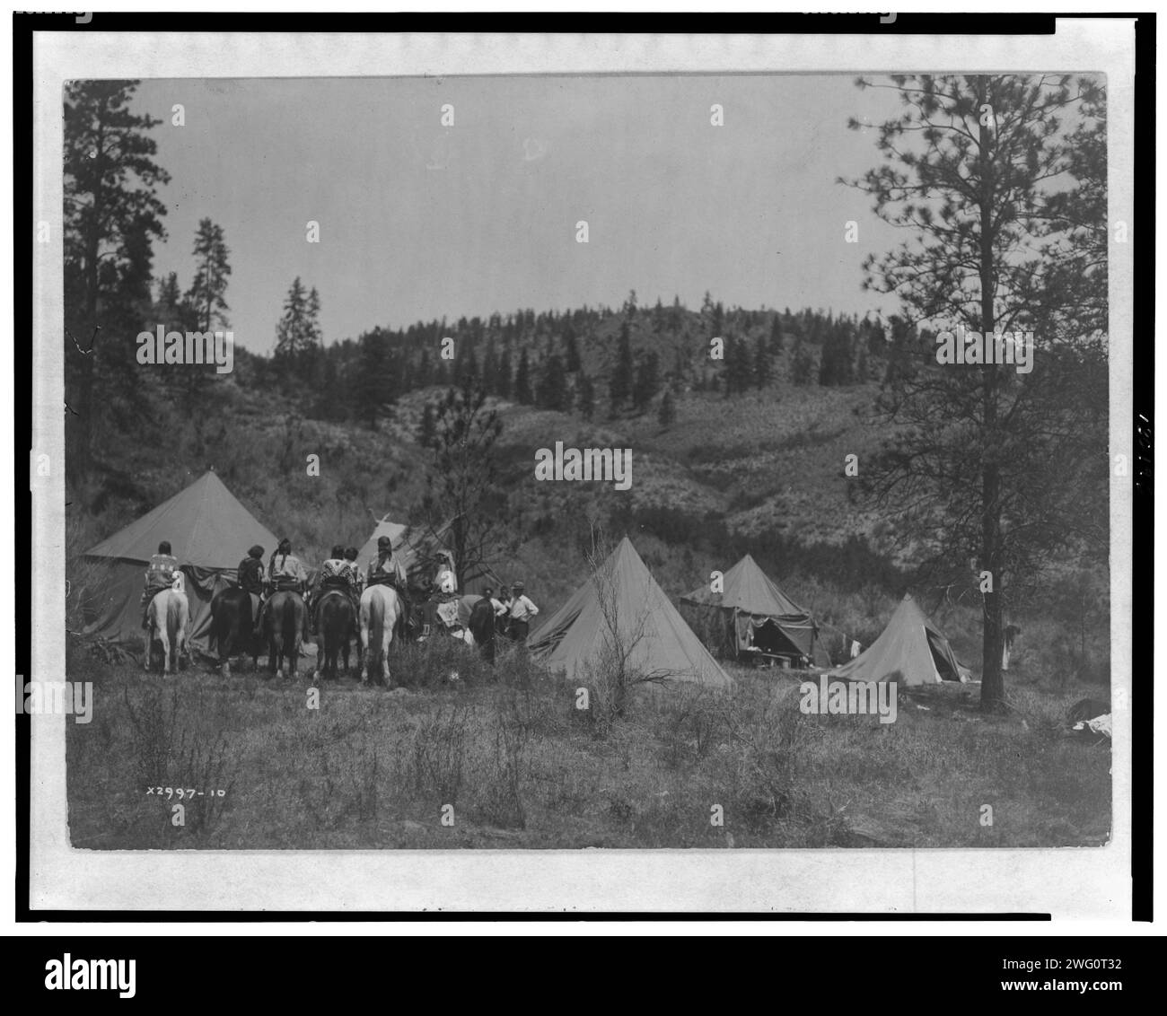 Autorenlager unter den Spokan, 1910. Fünf Zelte auf einer Rodung, Edward S. Curtis in der Mitte, Spokane Männer und Frauen auf dem Pferd links. Stockfoto