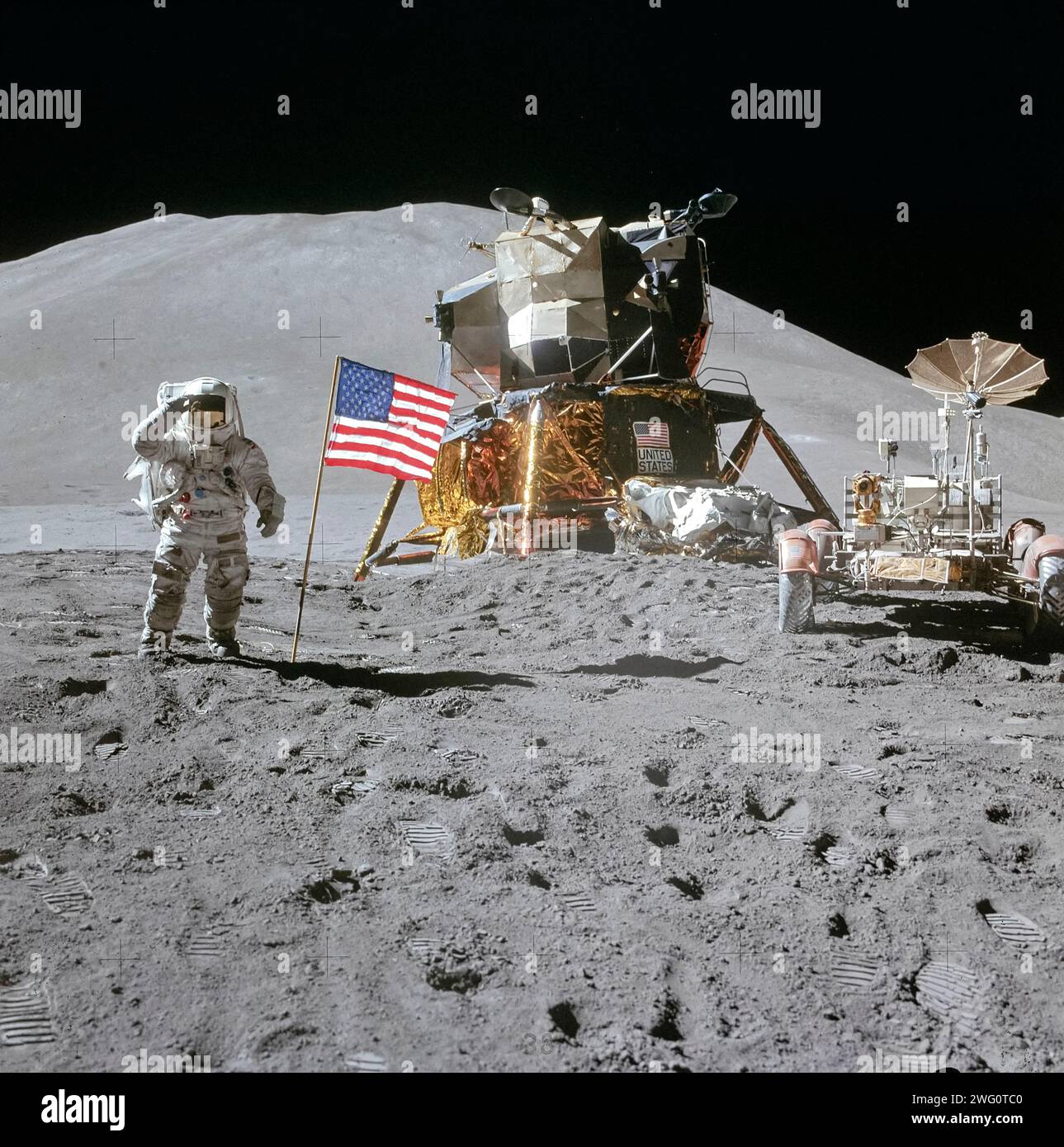 Apollo 15 Astronaut James Irwin grüßt am 1. August 1971 neben der amerikanischen Flagge neben dem Falcon Mondmodul und dem Lunar Roving Vehicle an der Landungsstelle Hadley-Apennin. Stockfoto