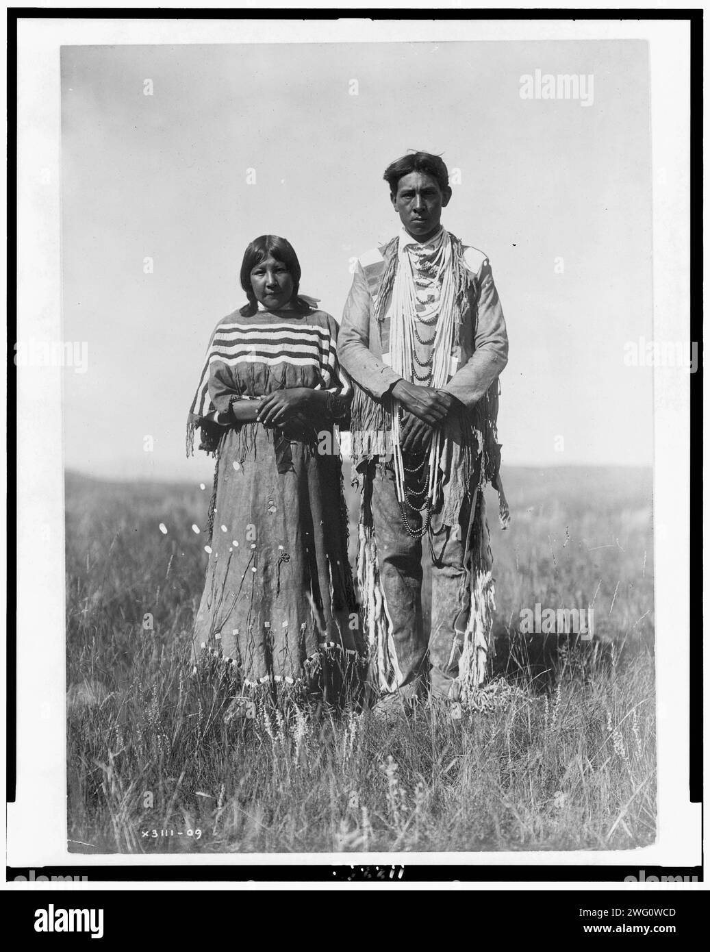 Joe Russell, 1910. Piegan-Mann und -Frau stehen in offener Prärie. Stockfoto