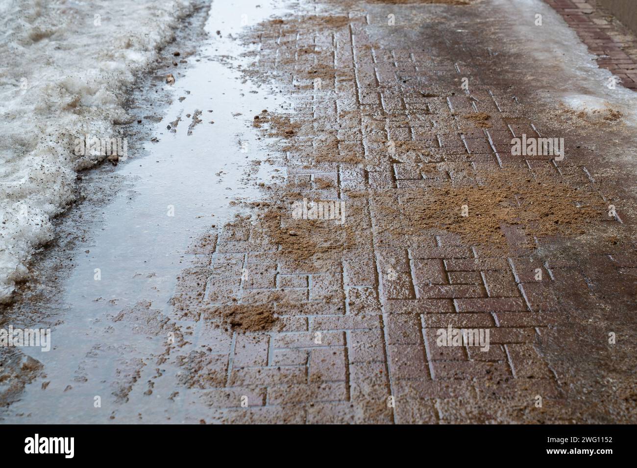 Straßenoberfläche mit technischem Salz und Sand behandelt, um Eisbildung zu verhindern, Salzpfützen auf der Straße Stockfoto