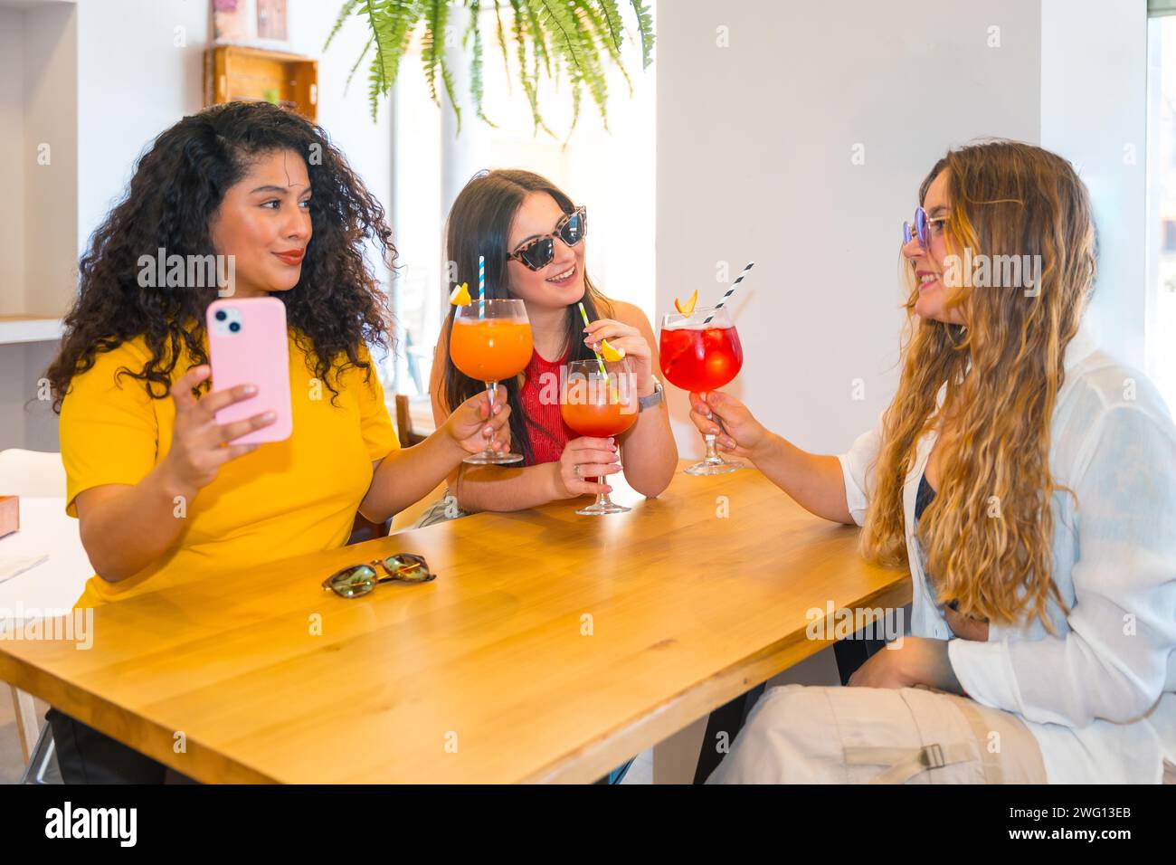 Drei Freundinnen, die in einer Bar Cocktails trinken Stockfoto