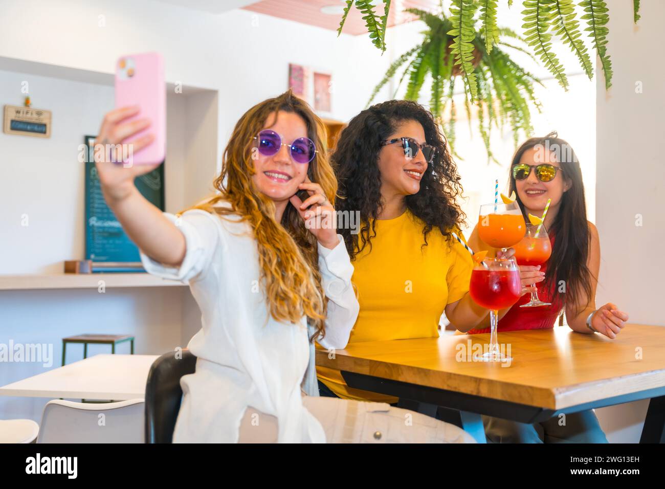 Drei Schönheitsfreunde machen Selfie, während sie Cocktails in einer Bar trinken Stockfoto