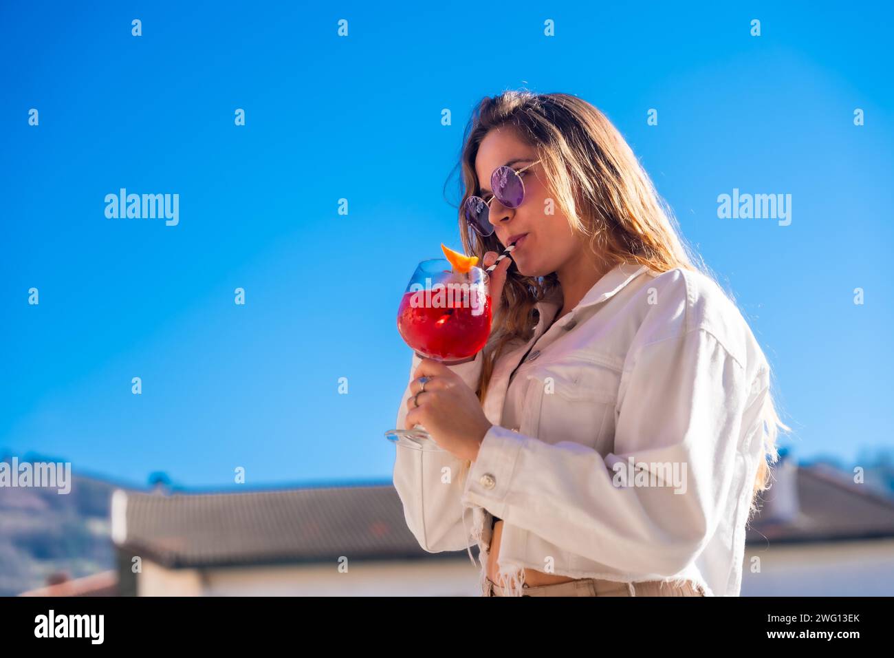 Blonde Frau lutscht einen Cocktail während einer Sommerparty auf dem Dach Stockfoto