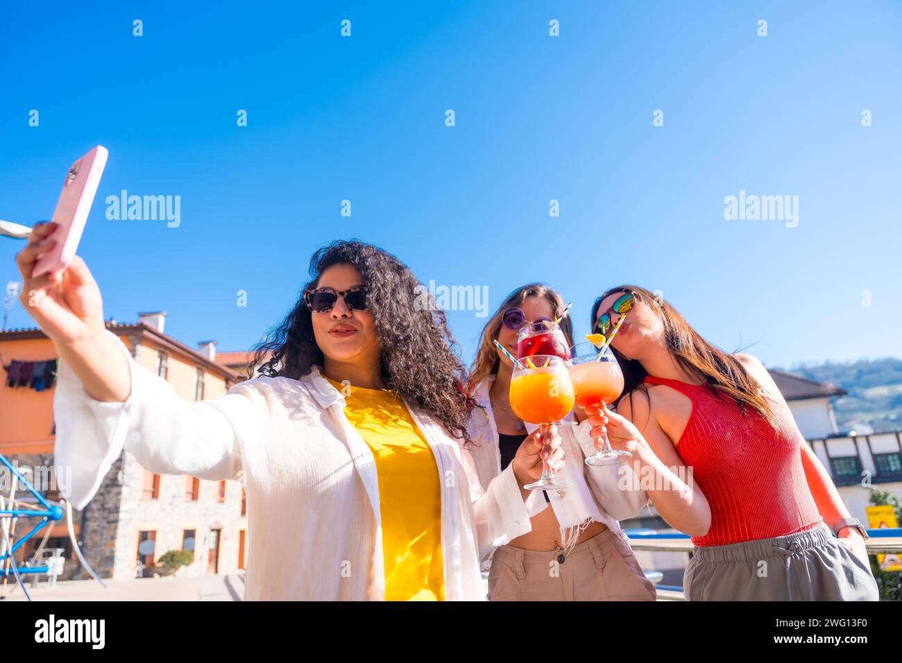 Freunde, die ein Selfie von einem traumhaften Sommertag machen und gemeinsam Cocktails auf einer Dachterrasse trinken Stockfoto