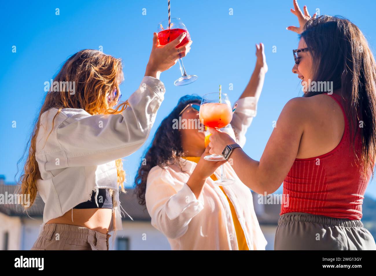Drei Frauen tanzen und trinken Alkohol auf der Dachparty im Sommer Stockfoto