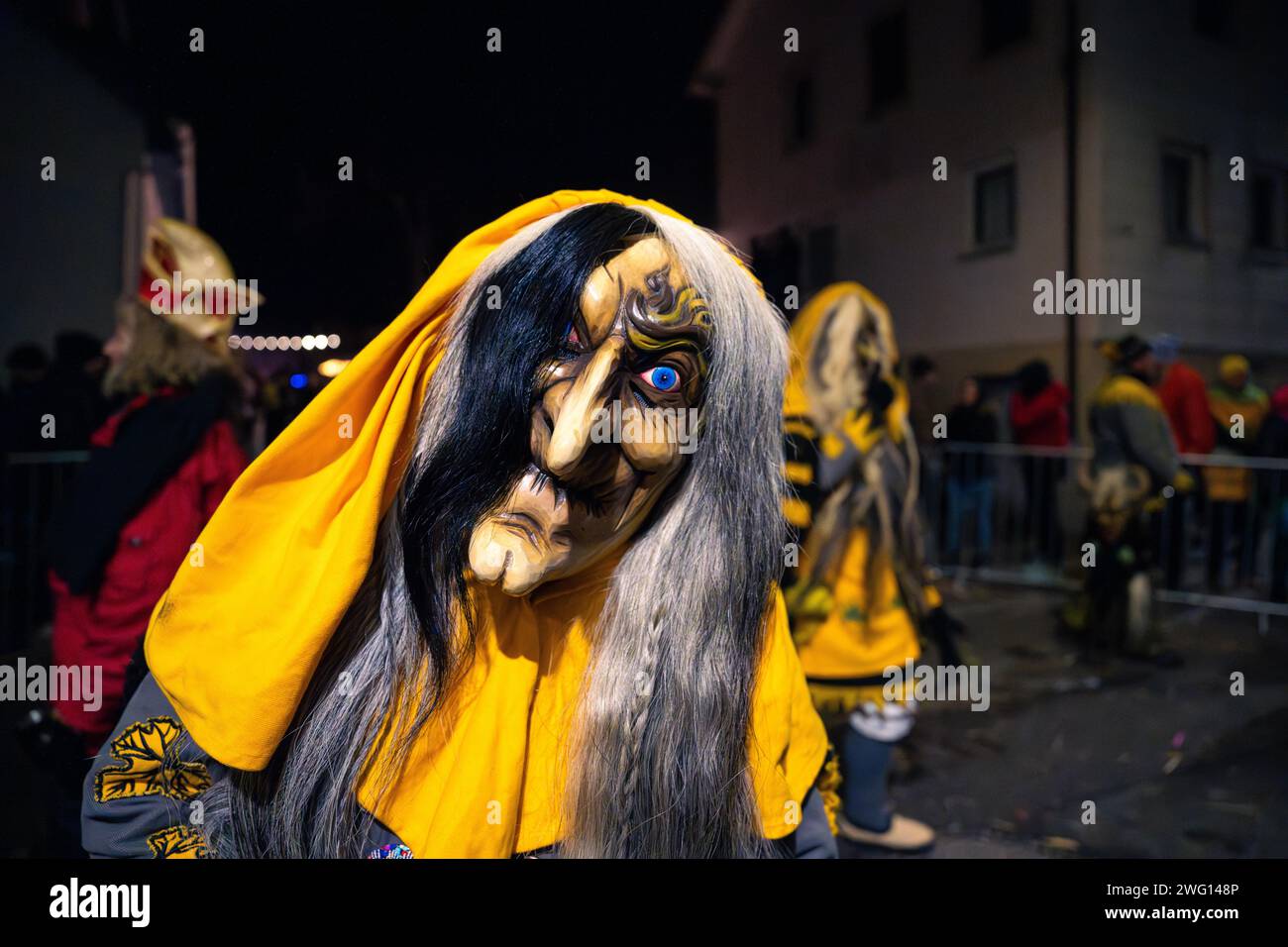 Person mit detaillierter Maske und gelbem Mantel bei Nacht, Karneval, Schellbronner Nachtparade, Schellbronn, Deutschland Stockfoto