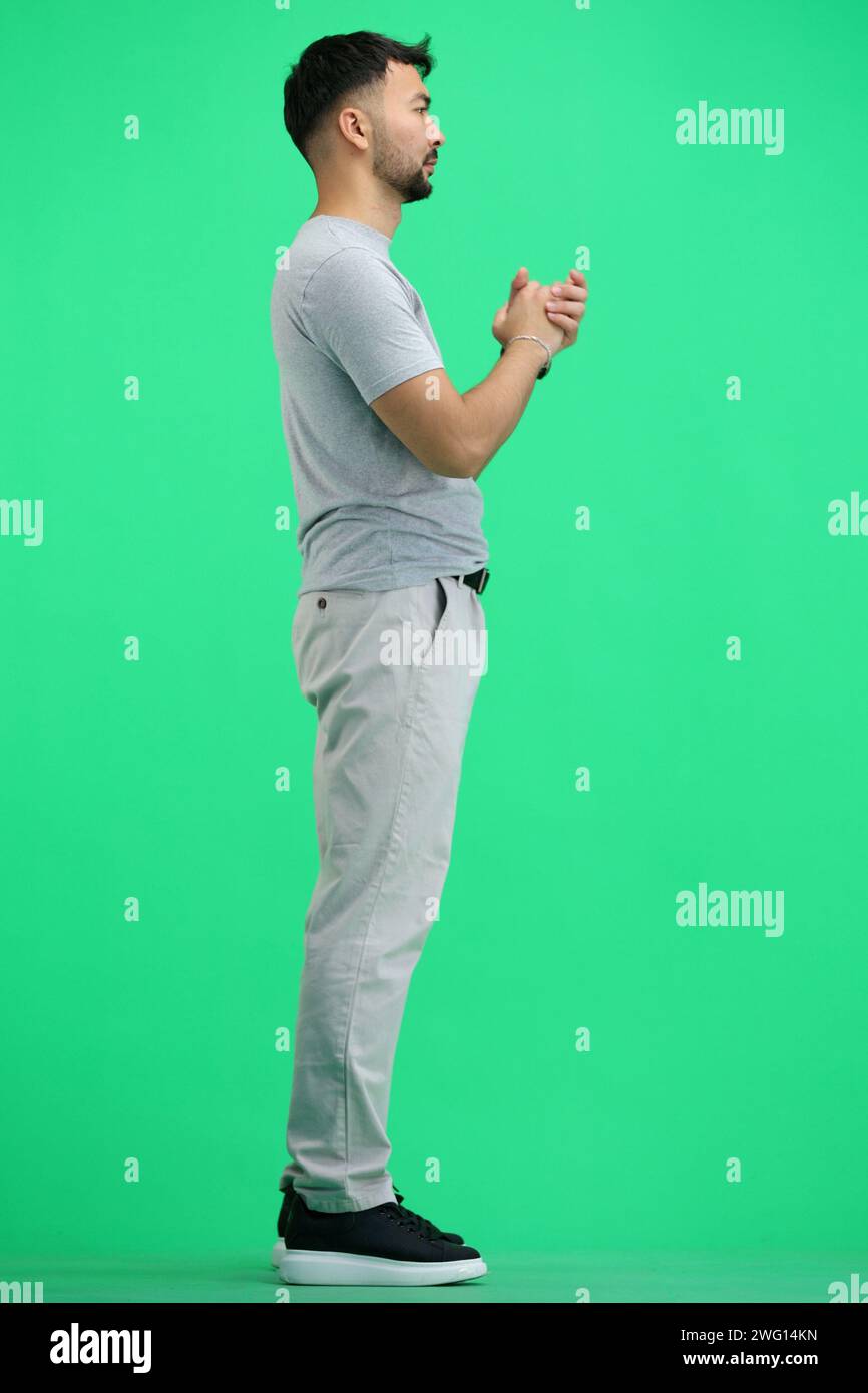 Ein Mann, voller Länge, auf grünem Hintergrund, fleht Stockfoto