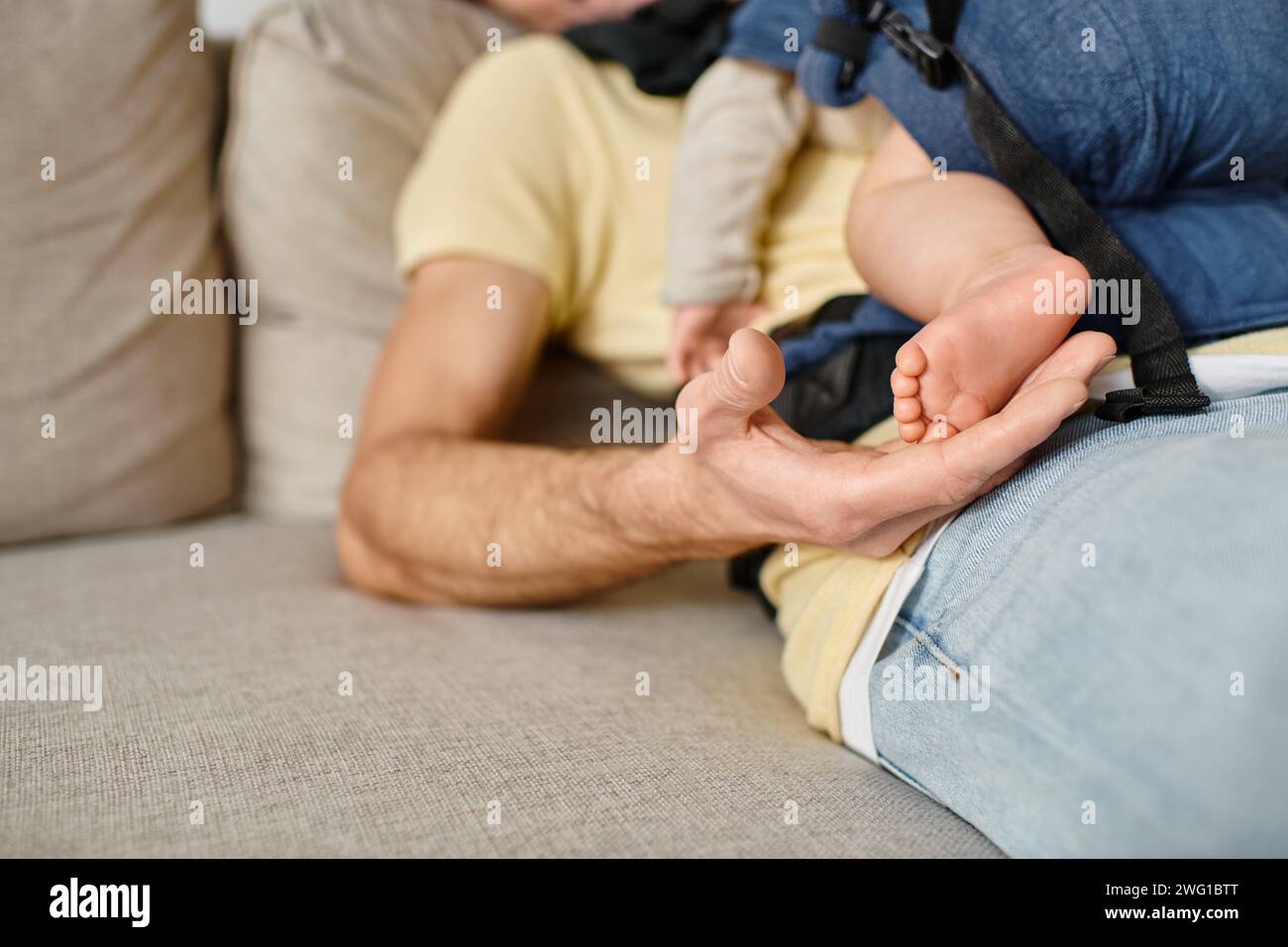 Nahaufnahme des Vaters, der die Füße seines kleinen Jungen hält, während er auf dem Sofa sitzt, Vaterschaft und Liebe Stockfoto