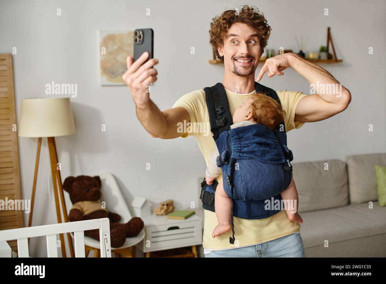 Fröhlicher Vater, der Selfie mit schlafendem Baby in Tragetasche, Vaterschaft und modernem Elternkonzept macht Stockfoto