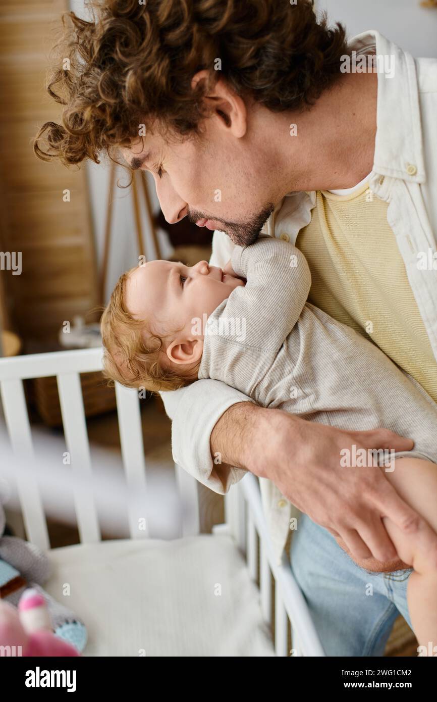 Liebevoller alleinerziehender Vater, der seinen kleinen Sohn aus der Kinderkrippe hebt, Vaterschaft und Liebe Stockfoto