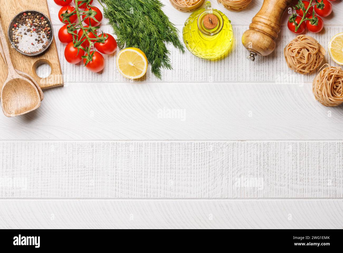 Kochszene: Kirschtomaten, Nudeln, Gewürze auf dem Tisch. Flache Ladefläche mit Kopierraum Stockfoto