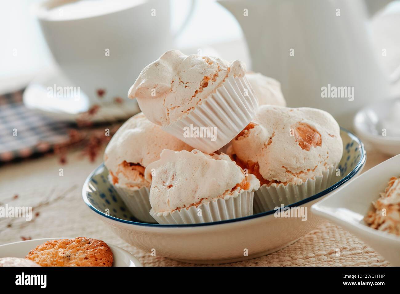 Einige Merengues almendrados, spanische Baisons mit Mandeln, serviert in einer Keramikschale auf einem Tisch mit brauner Tischdecke Stockfoto