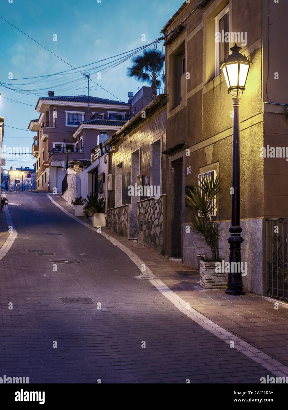 San Miguel de Salinas, Alicante - Spanien. Eine Straße in San Miguel de Salinas, beleuchtet von einer Straßenlaterne bei Sonnenuntergang an einem Januarabend. Stockfoto