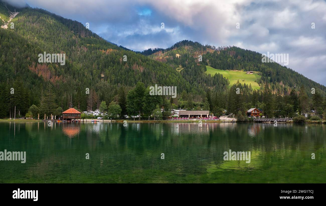 Atemberaubender bergblick mit Blick auf das ruhige Wasser, neben einem charmanten Wohnort: Toblacher See, Südtirol, Italien Stockfoto