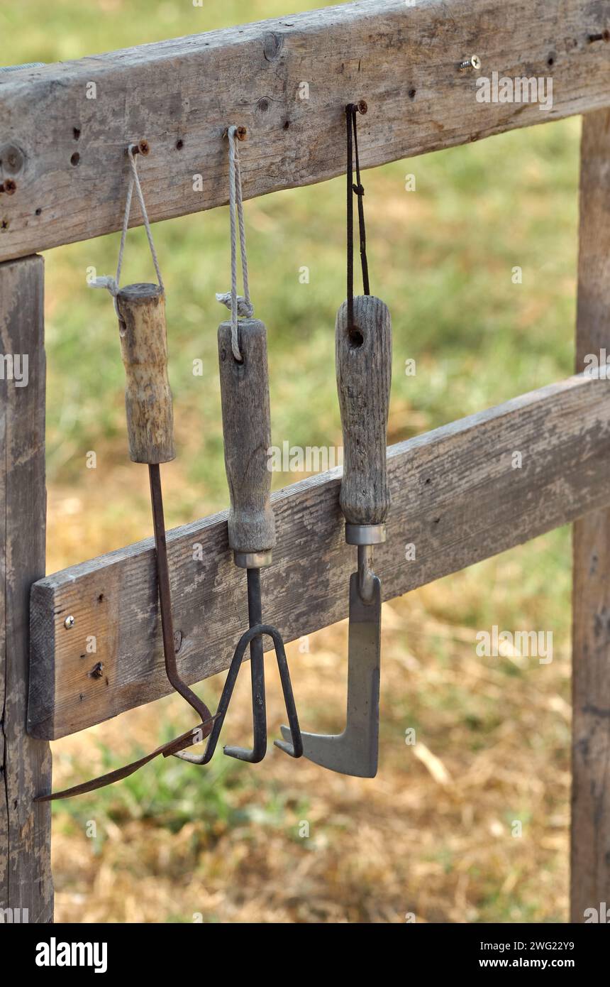Rostige Gartengeräte hängen auf dem Holzgestell Stockfoto