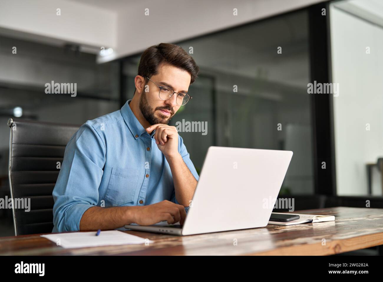Geschäftiger Geschäftsmann aus lateinamerika denkt über Online-Investitionen und arbeitet an Laptops. Stockfoto
