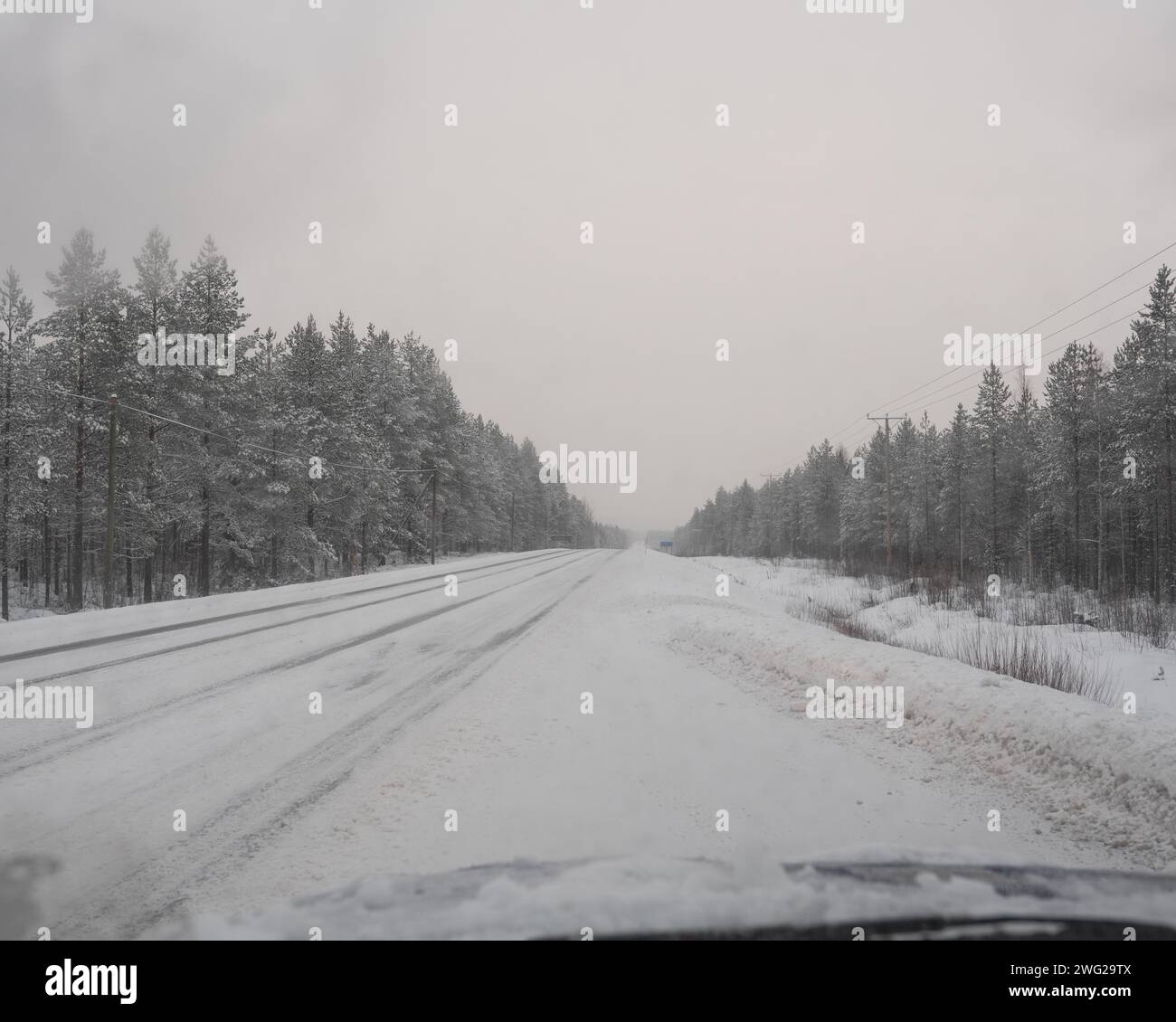 Eine vereiste und schneebedeckte Straße in Paltamo, Finnland im Winter. Die Straßenbedingungen sehen eisig und gefährlich aus. Stockfoto