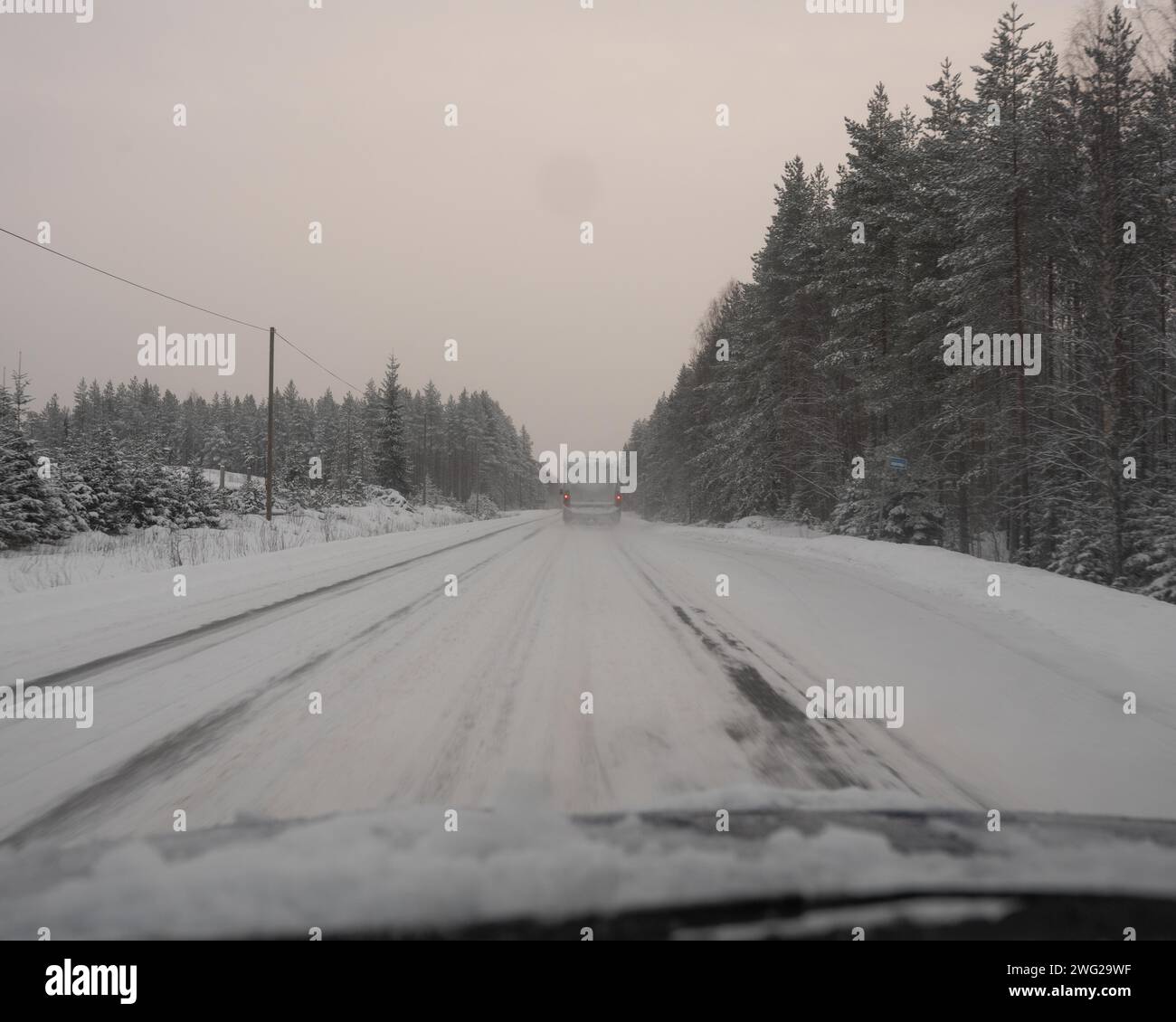 Eine vereiste und schneebedeckte Straße in Paltamo, Finnland im Winter. Die Straßenbedingungen sehen eisig und gefährlich aus. Stockfoto