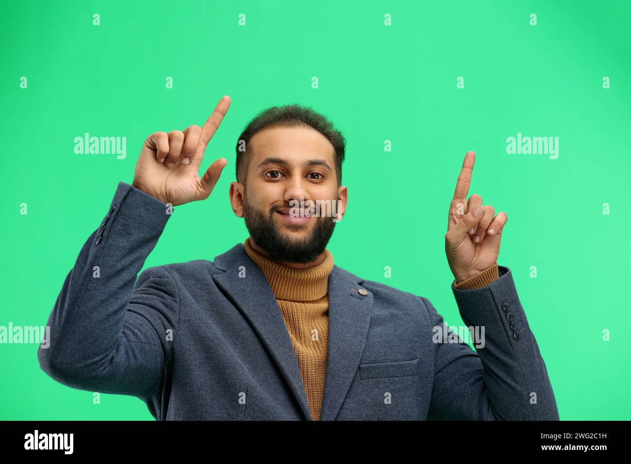 Mann, Nahaufnahme, auf grünem Hintergrund, zeigt nach oben Stockfoto