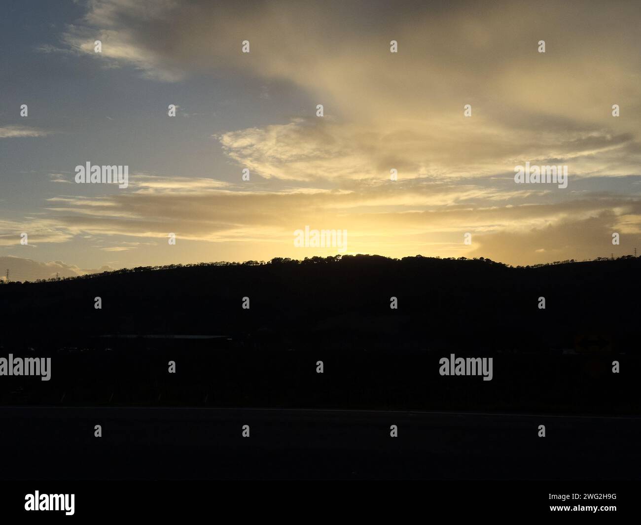 Sonnenaufgang über Hügel und Wolken vom Fenster des Appartements Stockfoto