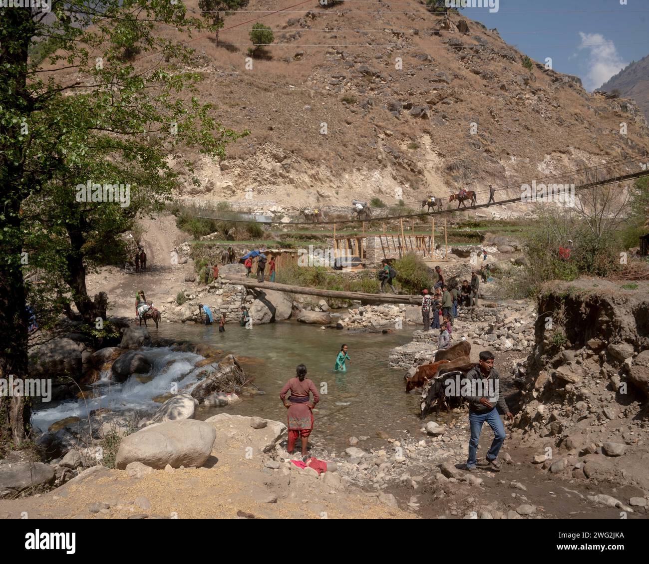 Eine lebendige Flussszene in Sarkegad, einem ländlichen nepalesischen Bergdorf in Humla. Nepalesische Frauen in traditioneller Kleidung waschen sich im Fluss. Stockfoto