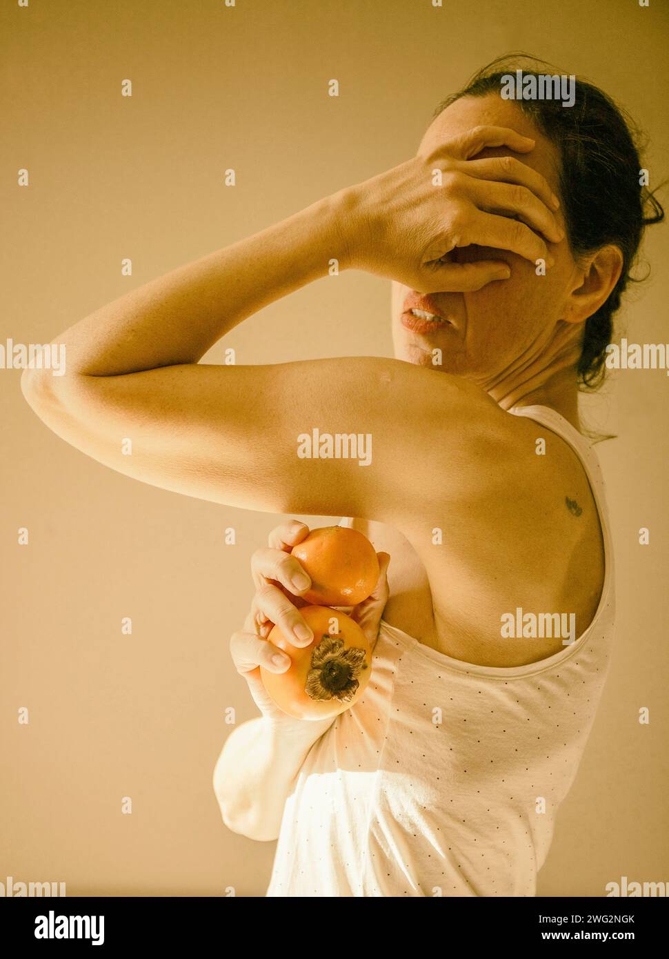 Frau mit einer Persimmon und einer Mandarine in der Hand, frankreich Stockfoto