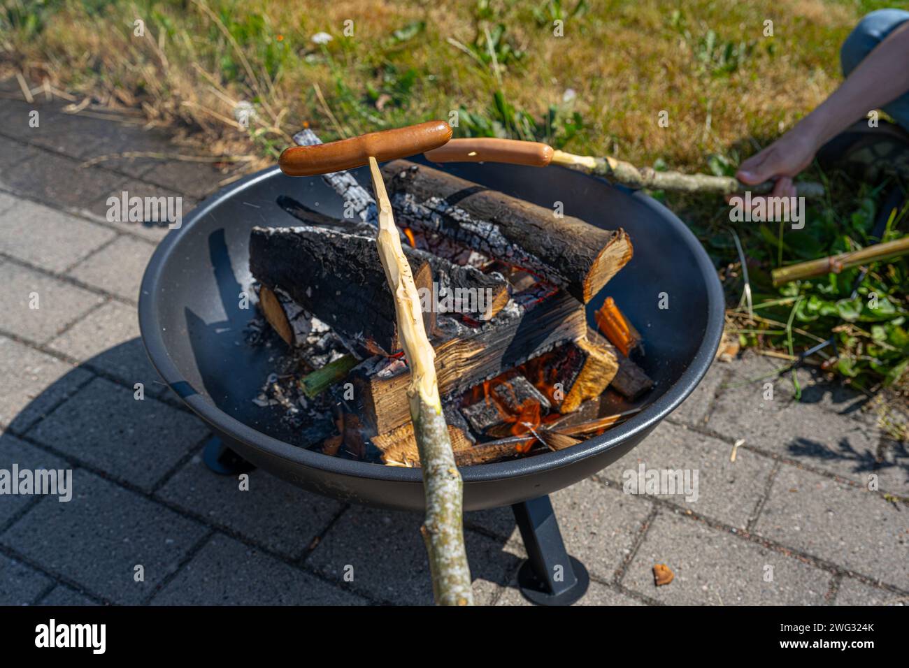 Hot Dogs auf Stöcken über einem Feuer Stockfoto