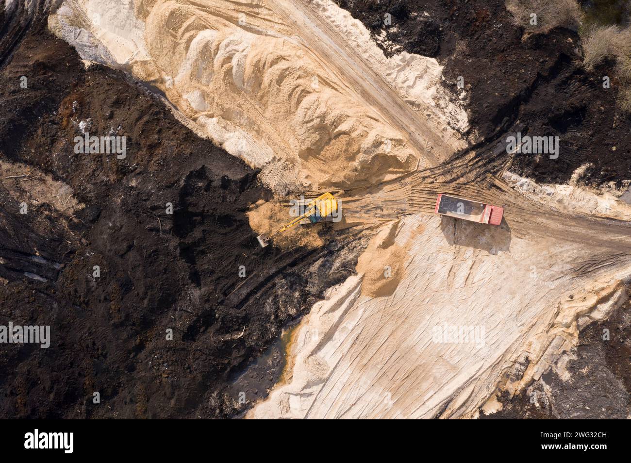 Luftaufnahme von Bagger und Lkw, die auf der Baustelle arbeiten. Stockfoto