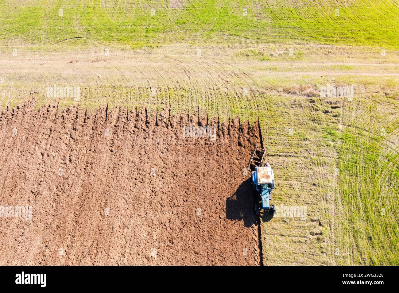 Draufsicht des Pflügens des Traktors auf dem landwirtschaftlichen Feld. Agrarbetriebskonzept. Boden für die neue Ernte vorbereiten. Stockfoto