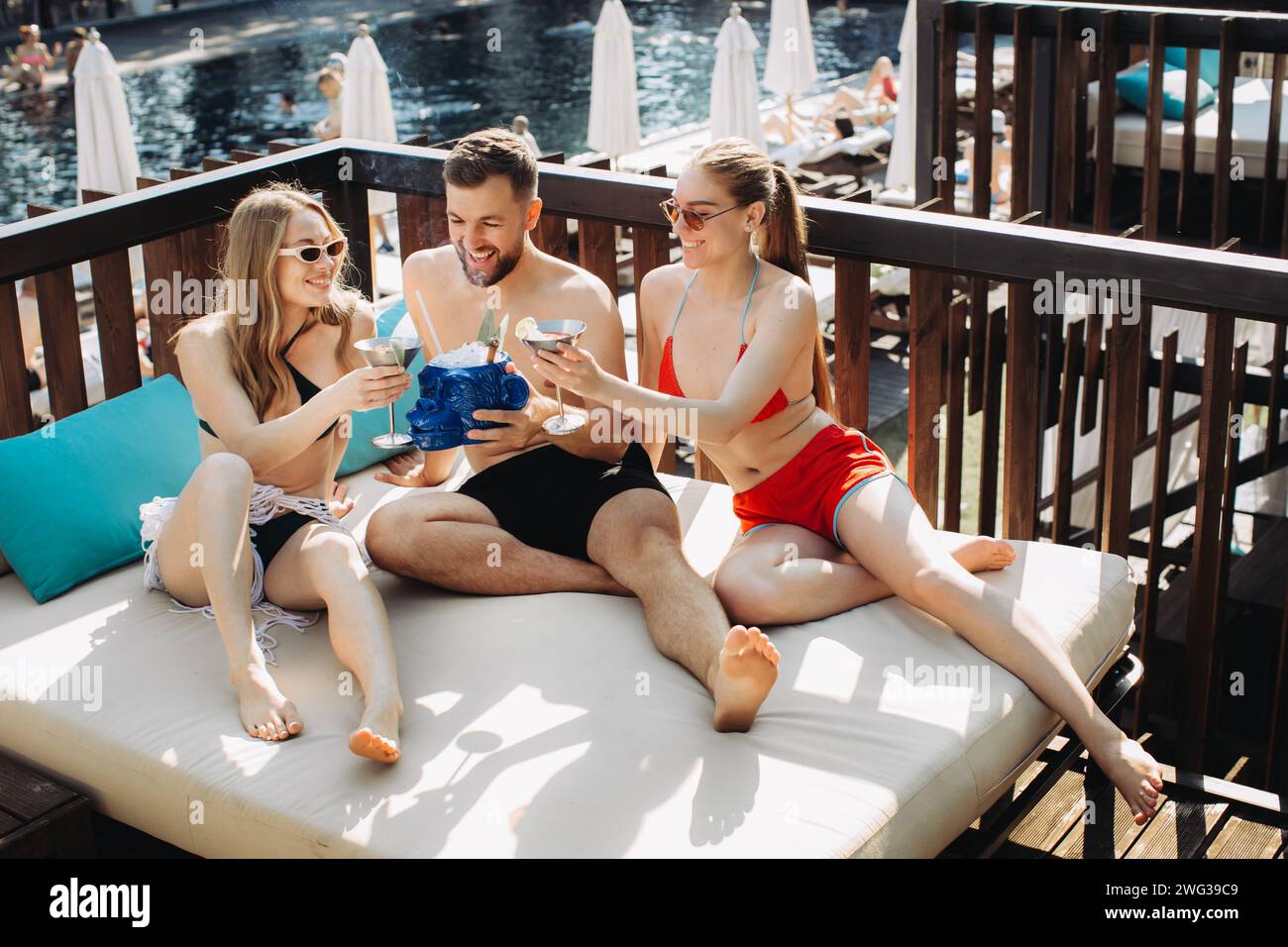 Eine fröhliche Gruppe von Freunden entspannt sich mit Cocktails am Pool. Stockfoto
