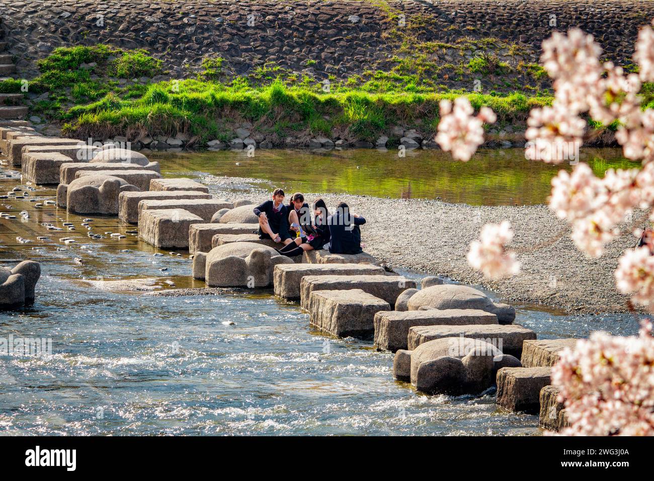 Japanische Schulmädchen spielen in Kamo River Stepstones Stockfoto
