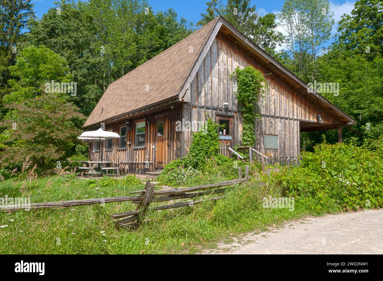 Ein altes Haus mit einem wackeligen alten Zaun im Wald in der Nähe einer Forststraße Stockfoto