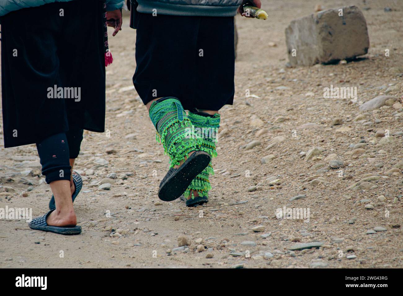 Schließen Sie bis zu zwei schwarze hmong-Frauen, die gehen und ihre ethnischen Beinornamente tragen, und zeigen Sie das authentische tägliche Leben und die Kultur im Lao Chai Village Sa Stockfoto