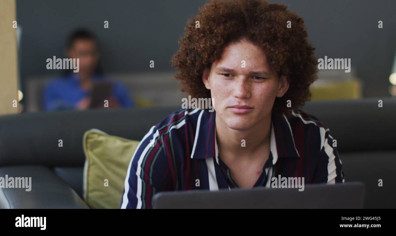 Ein junger birassischer Mann arbeitet zu Hause an einem Laptop Stockfoto
