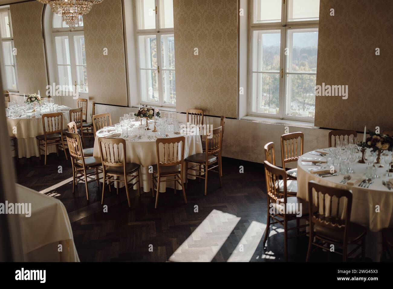Tisch für den Hochzeitsempfang mit Blumenarrangements, Kerzen und eleganten Sitzgelegenheiten Stockfoto