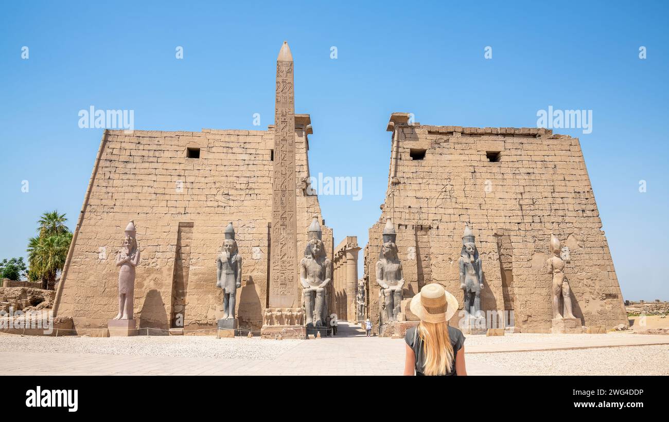 Luxor, Ägypten - Eine blonde Frau mit Strohhut schaut auf den Eingang zum Luxor-Tempel in Luxor, Ägypten Stockfoto