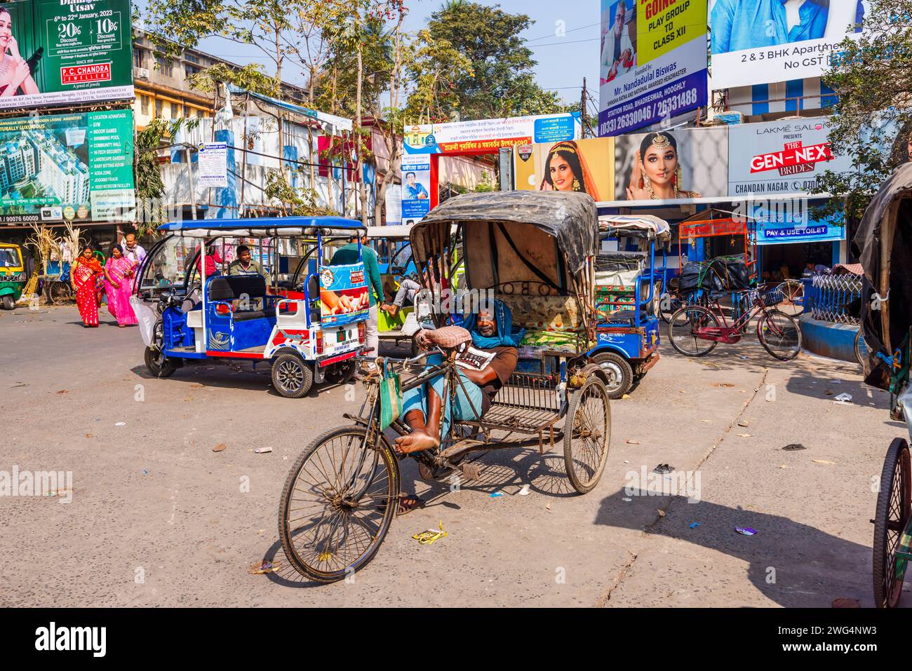 Ein lokaler Rikscha-Fahrer, der in einer Straßenszene im geschäftigen Stadtzentrum von Chandannagar (Chandernagore), Westbengalen, Indien, auf Geschäfte wartet Stockfoto