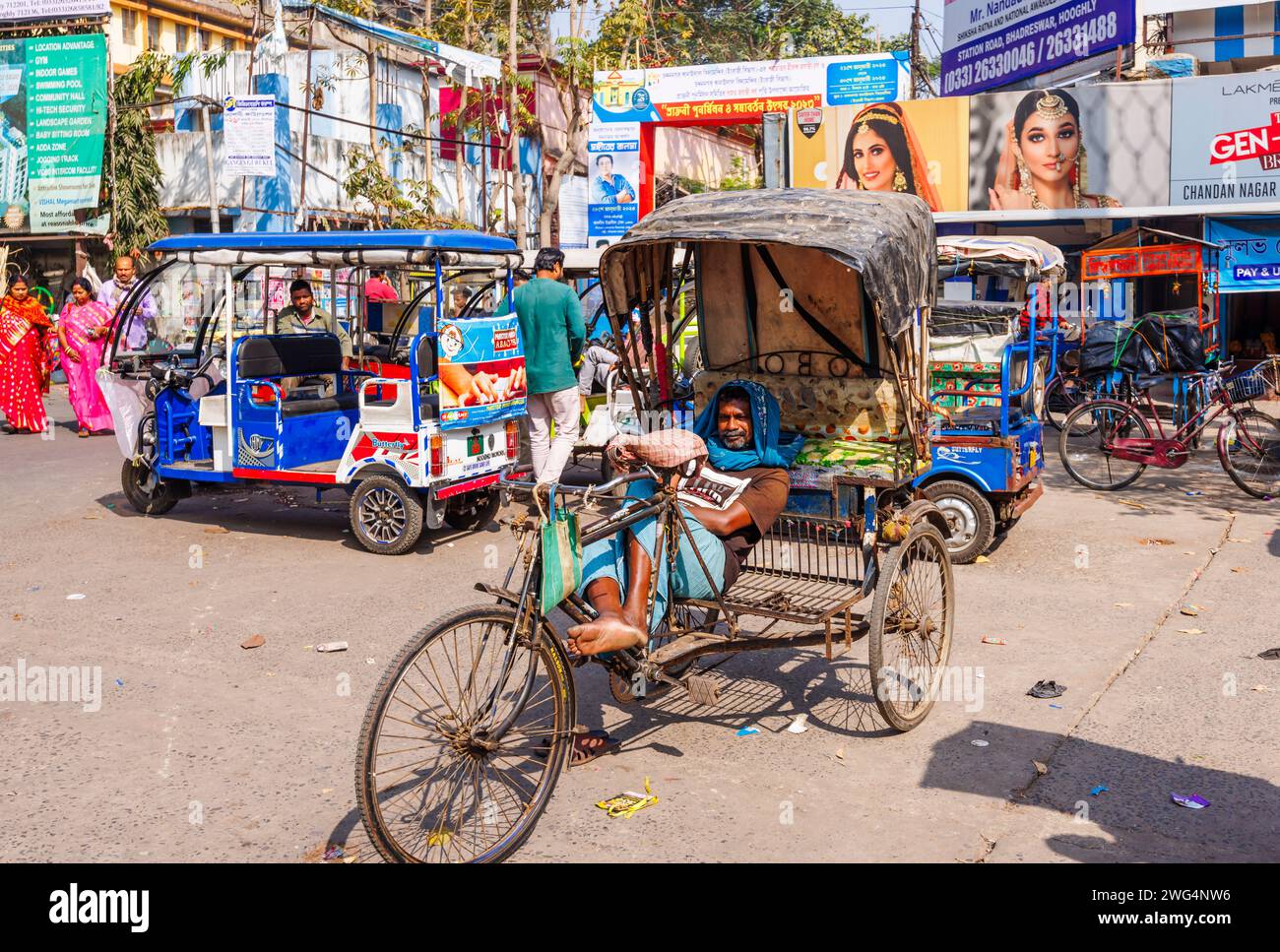 Ein lokaler Rikscha-Fahrer, der in einer Straßenszene im geschäftigen Stadtzentrum von Chandannagar (Chandernagore), Westbengalen, Indien, auf Geschäfte wartet Stockfoto