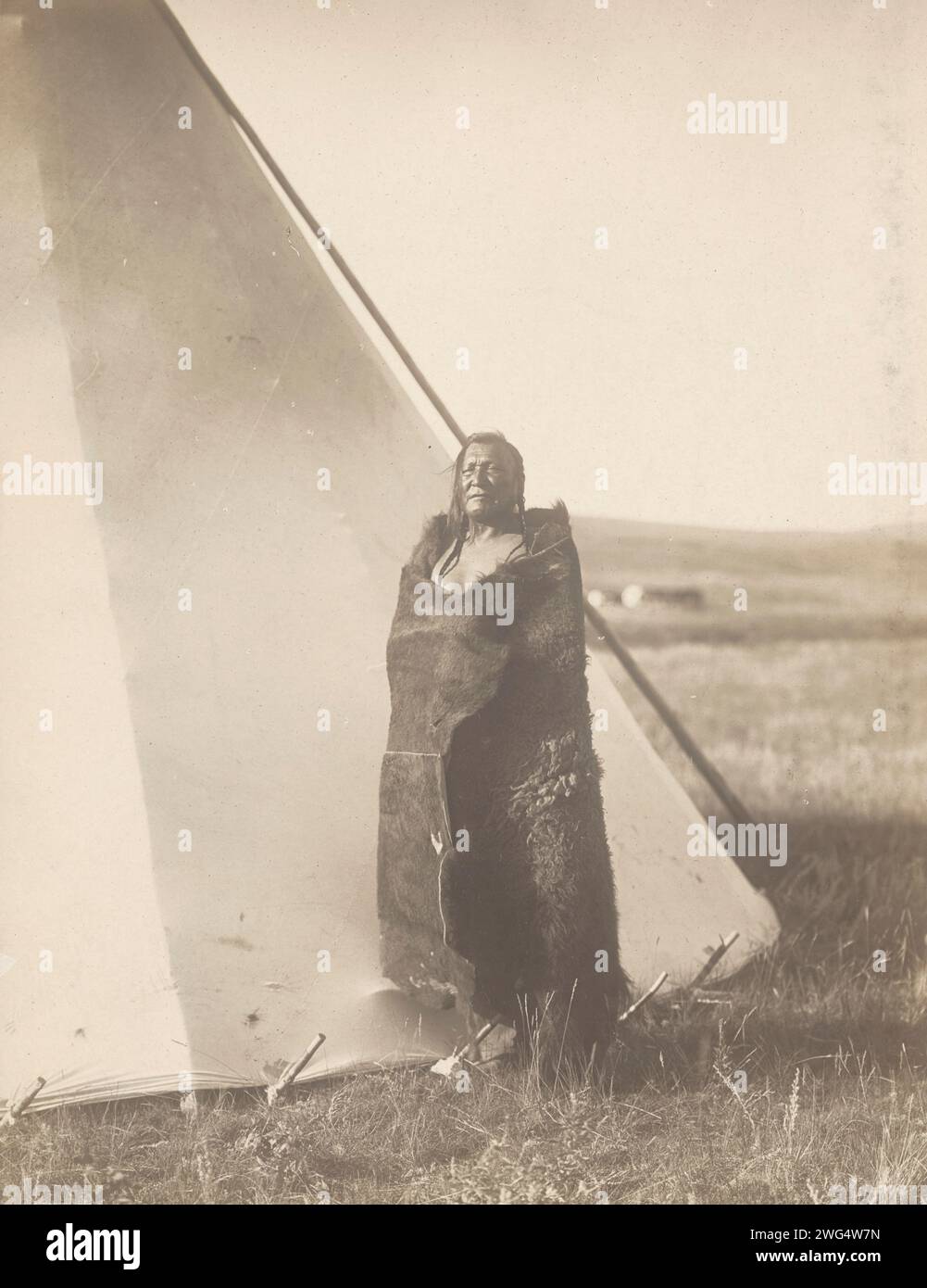 Berghäuptling, 1910. Das Foto zeigt den Berghäuptling, eingewickelt in Büffelfell, der außerhalb des Tipi steht. Stockfoto