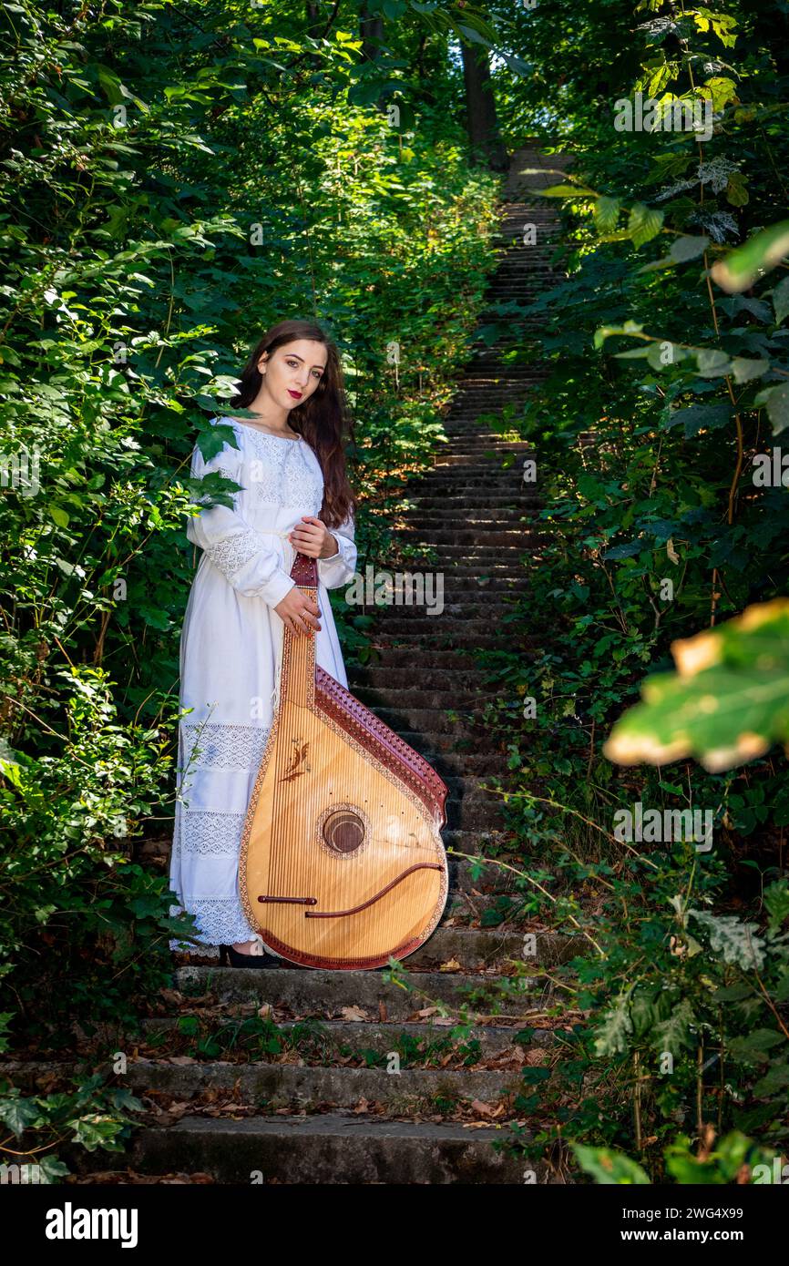 Ein junger Bandura-Spieler mit Bandura steht auf alten Steintreppen im Park Stockfoto