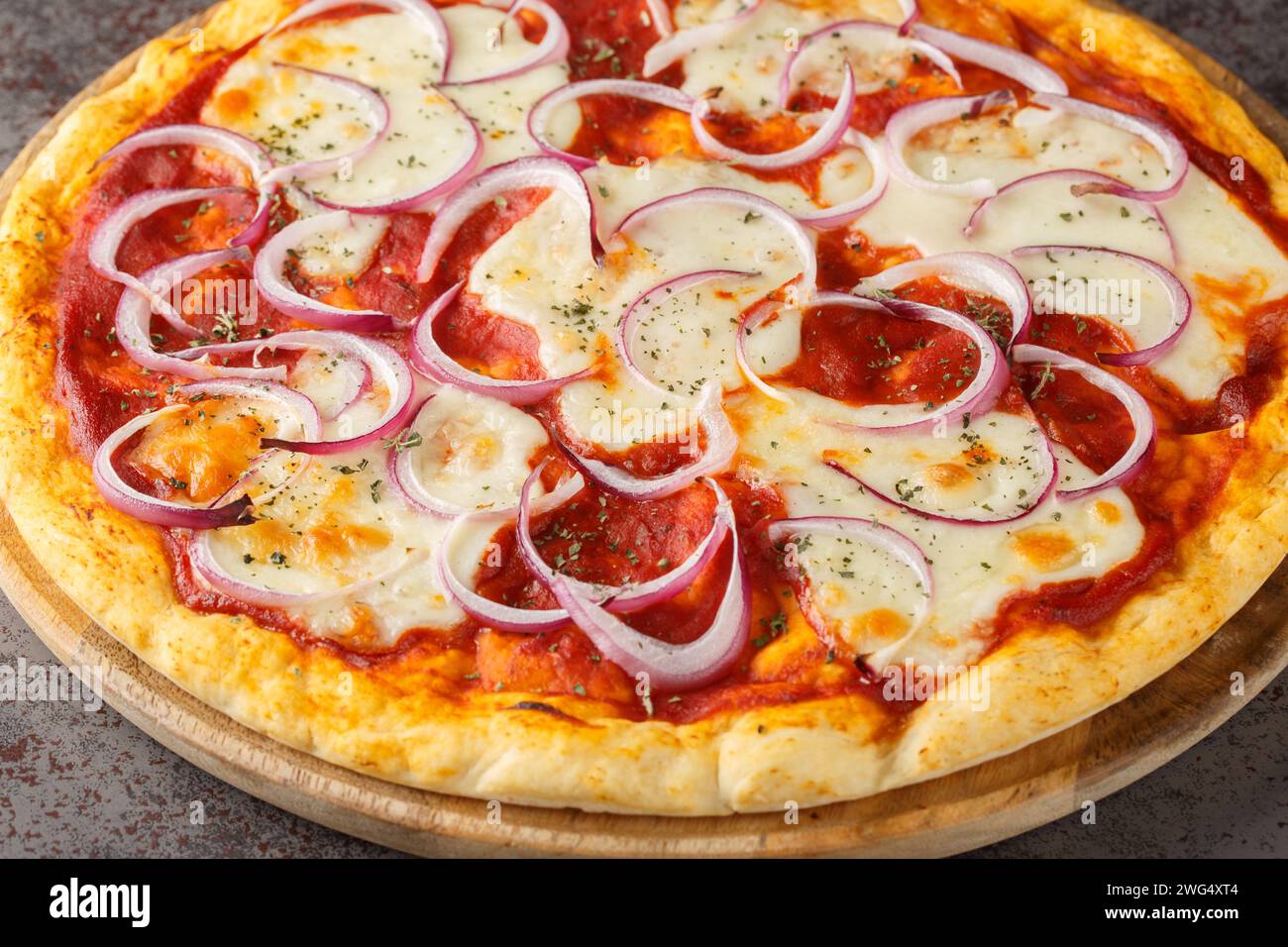 Pizza pugliese ist eine dünne Pizza, die mit Tomatensauce, Käse und vielen Zwiebeln auf einem Holzbrett auf dem Tisch bedeckt ist. Horizontal Stockfoto