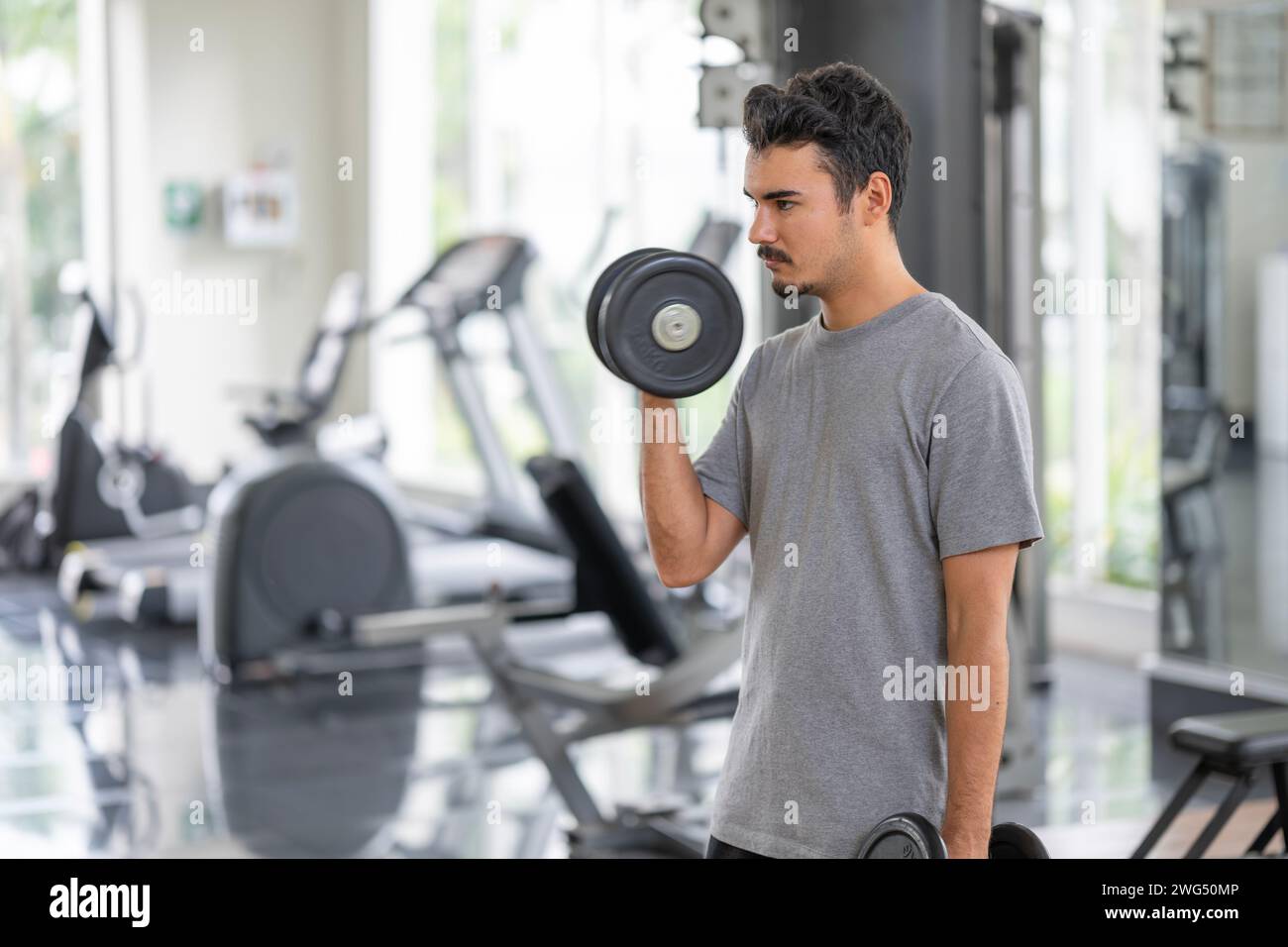 Ein Mann in Nachsicht, der sich darauf vorbereitet, Gewichte zu heben. Dieses Bild fängt den Moment der mentalen Vorbereitung in Sport und Fitness ein.mentale Vorbereitung für p Stockfoto