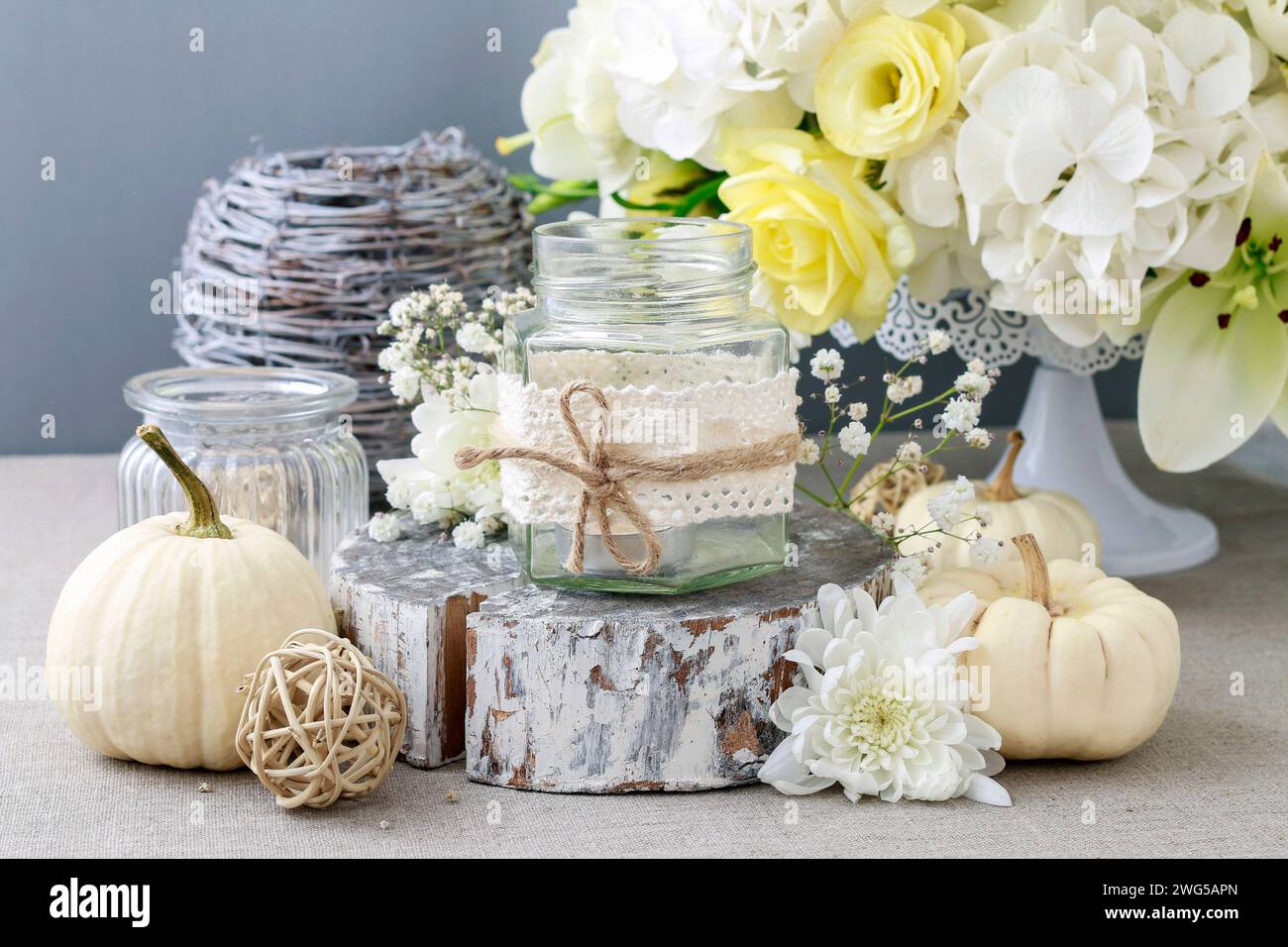 Glas verziert mit Spitze und Zeichenfolge, weiße Kürbisse und luxuriöse Blumen herum. Stockfoto